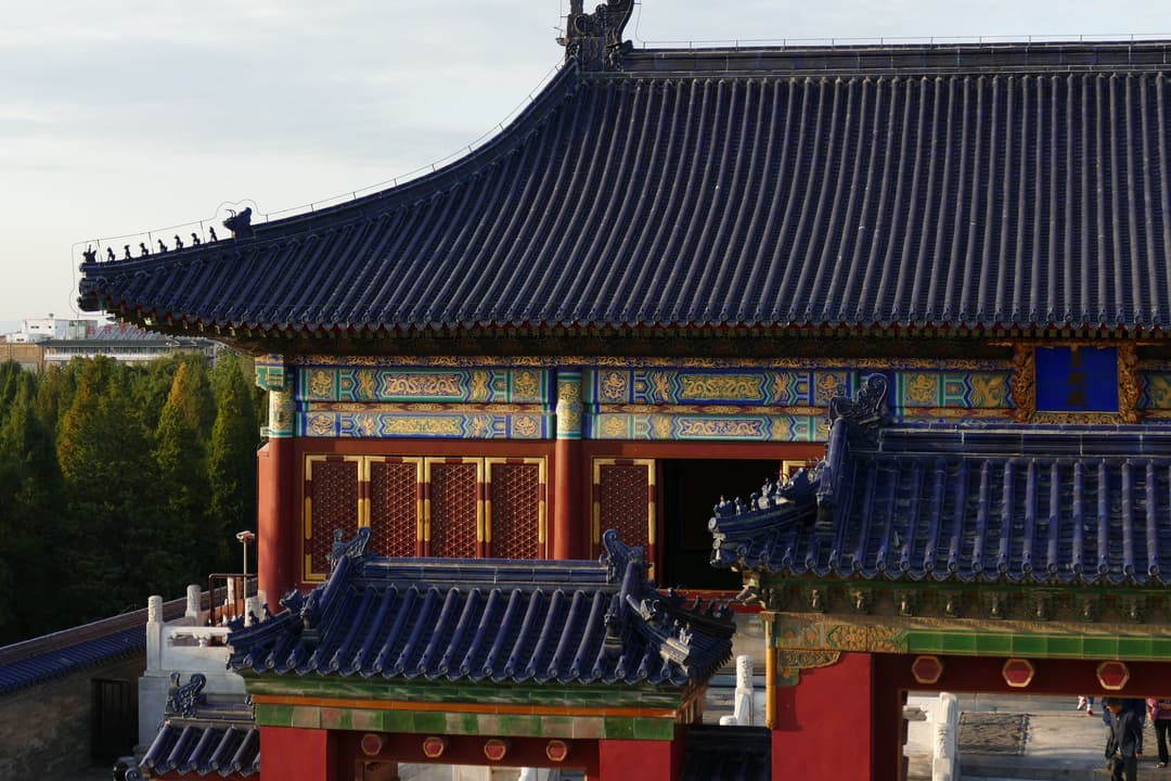 Detail of blue glazed tile roofs and ornate eaves in warm sunlight