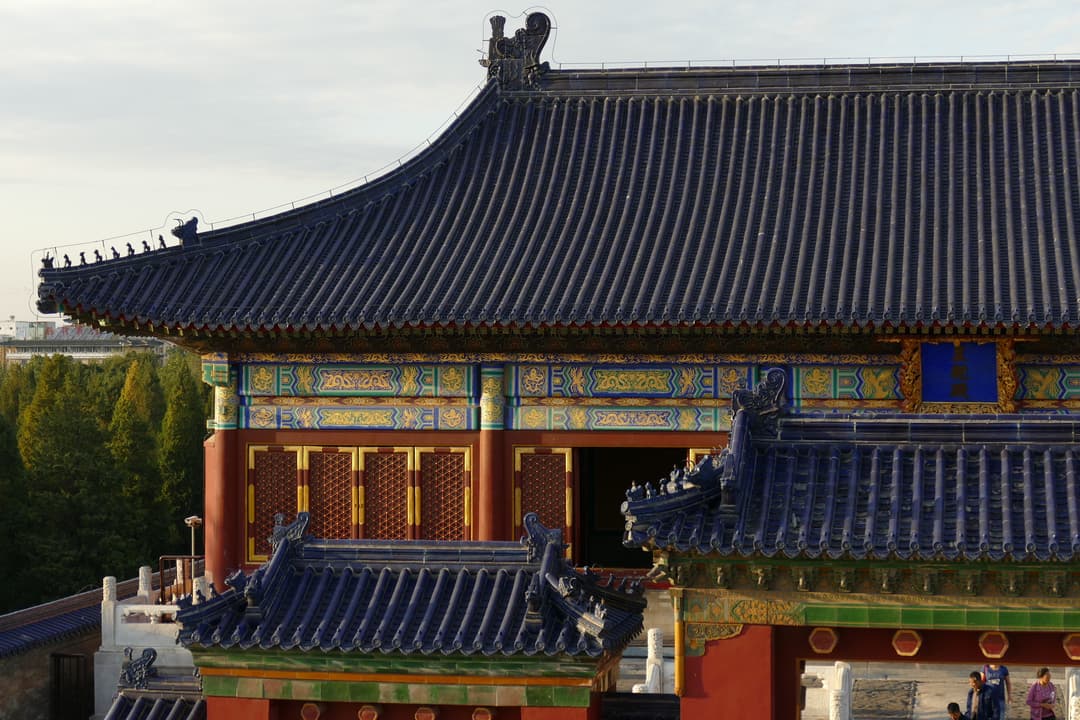 Detail of blue-glazed roof tiles and painted beams in late afternoon light