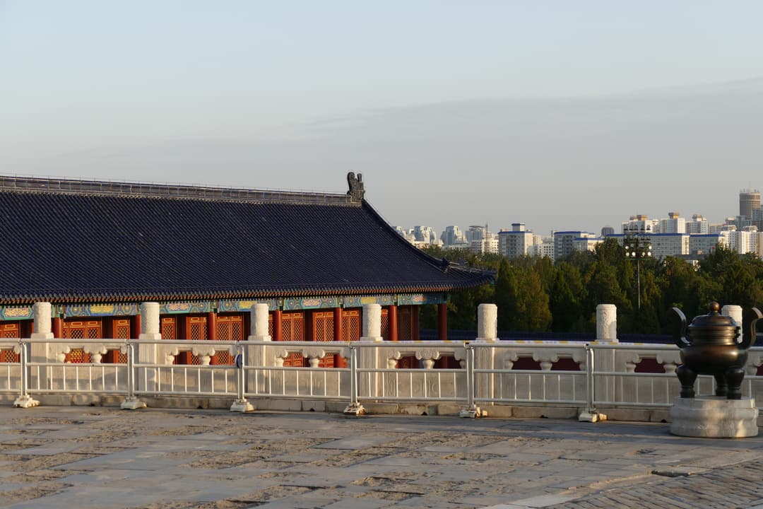 Terrace with bronze censer and blue-tiled hall in late afternoon light.