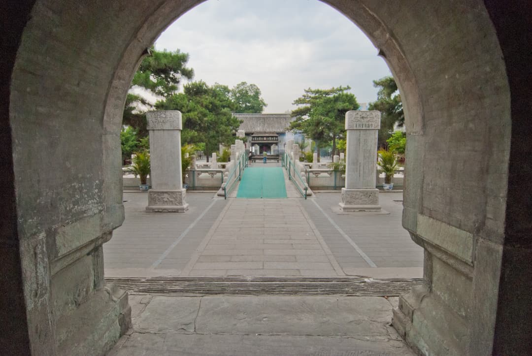 View through a stone archway toward the bridge and inner courtyard.