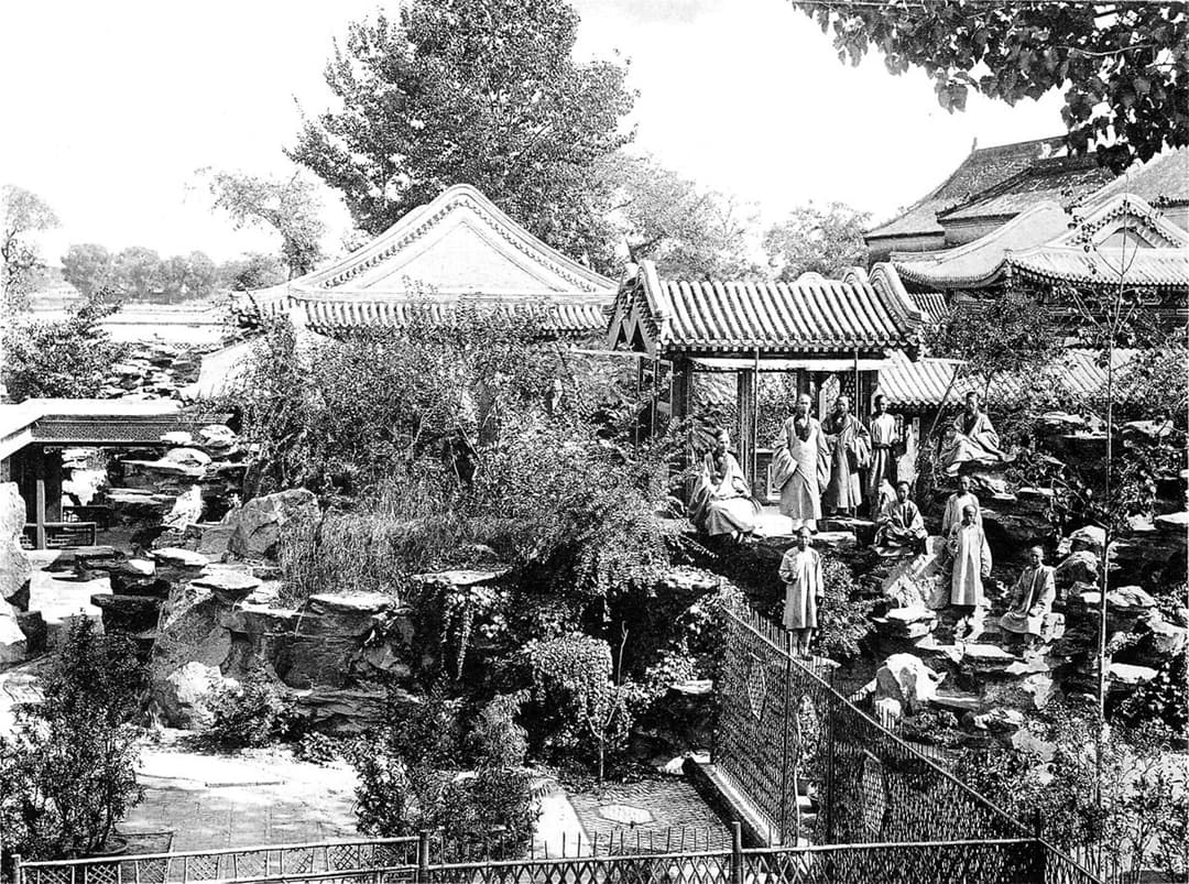 Taoist monks posed on the rockery in the garden of White Cloud Temple