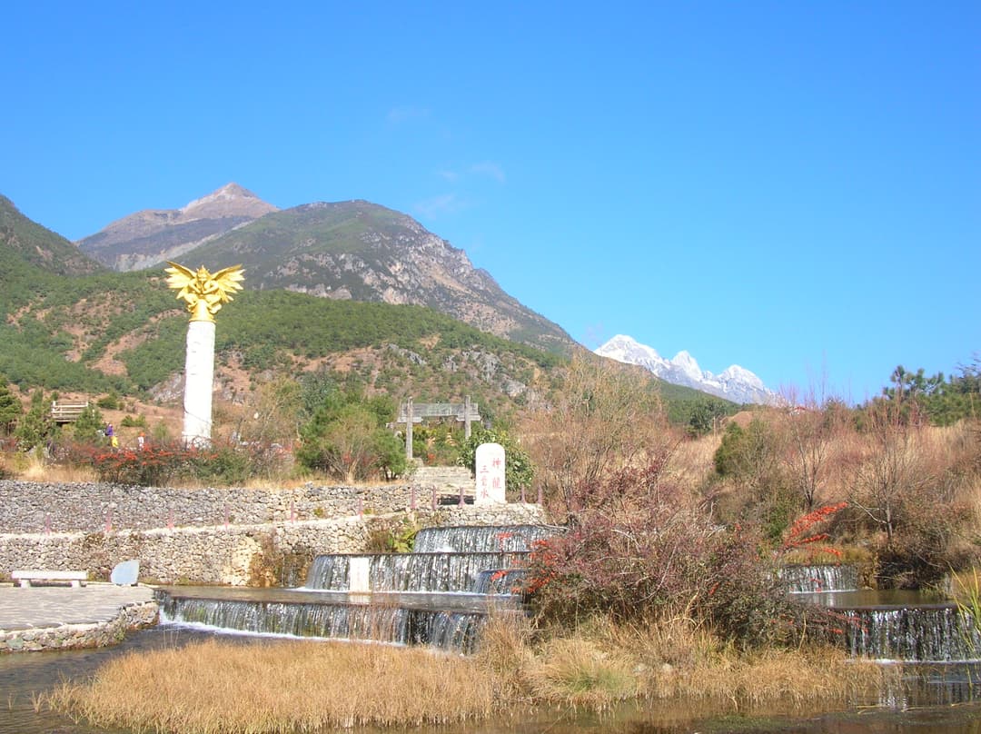 Wide view of golden Garuda column and terraced spring at Jade Water Village.