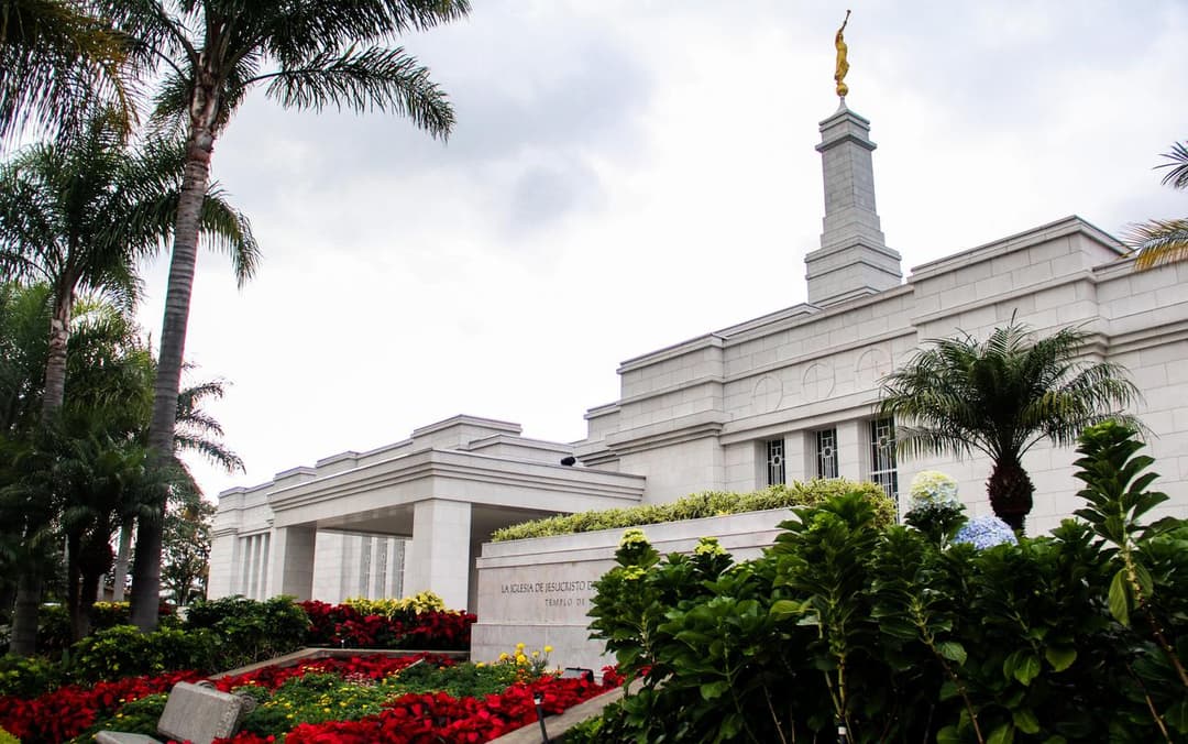 Low-angle view of the San José Costa Rica Temple spire and tropical gardens.