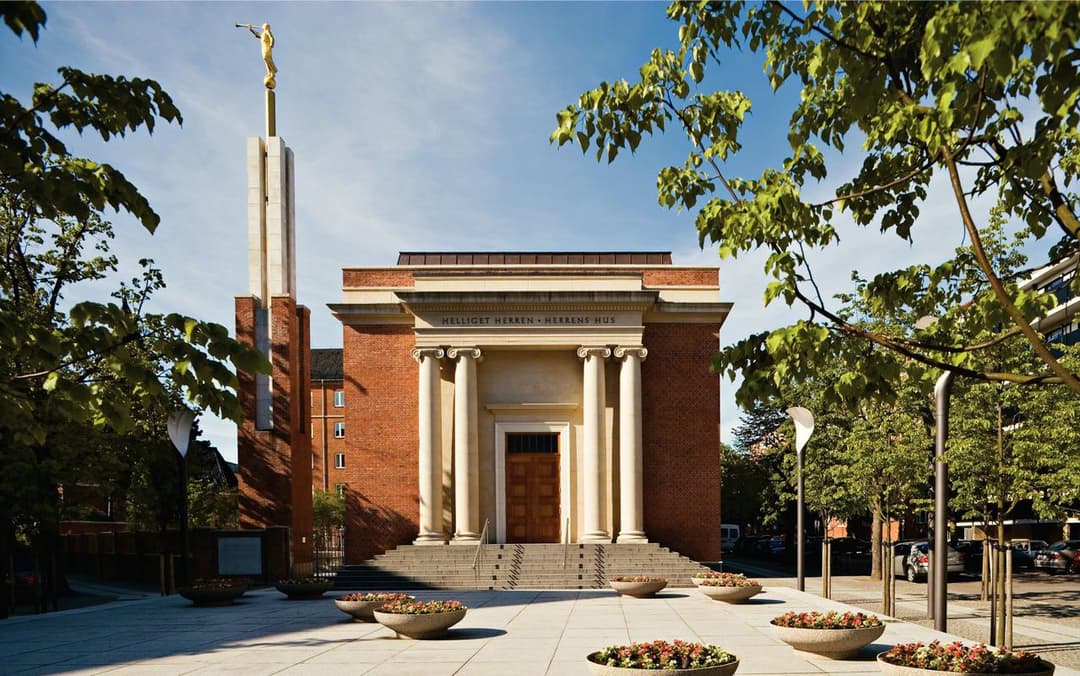 Front entrance and spire of the Copenhagen Denmark Temple, framed by trees.