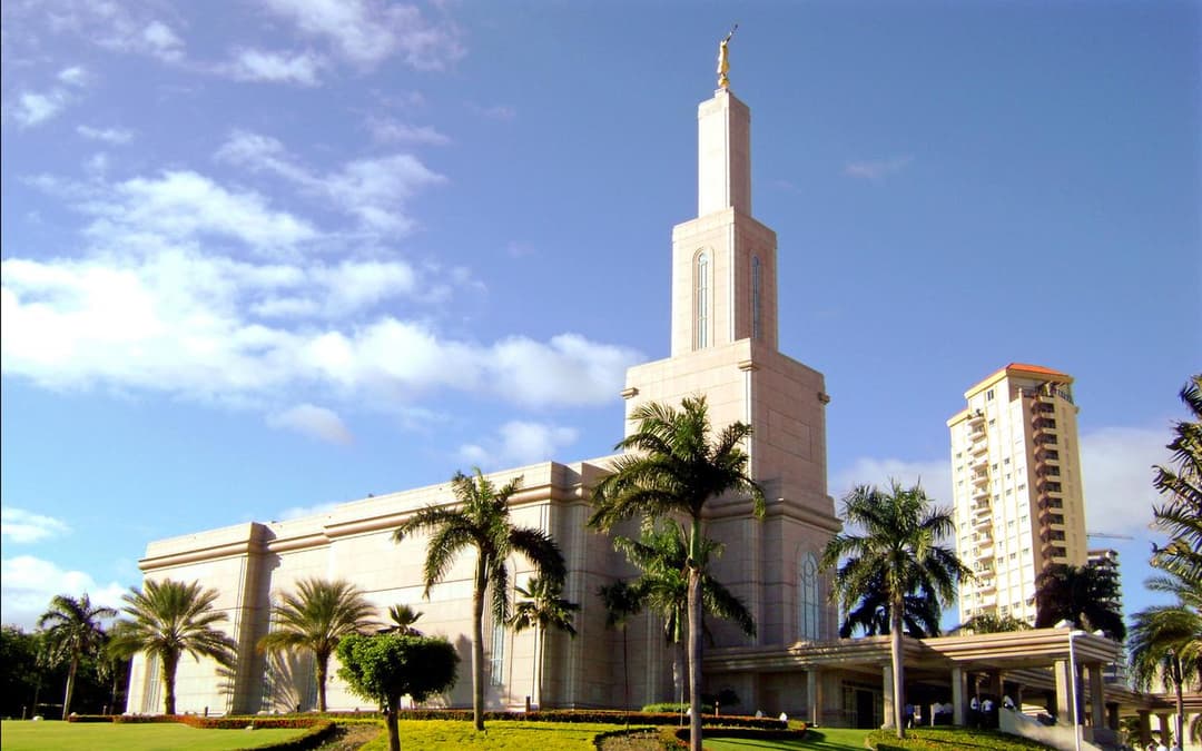 Wide exterior view of the temple spire and tropical grounds on a sunny day.