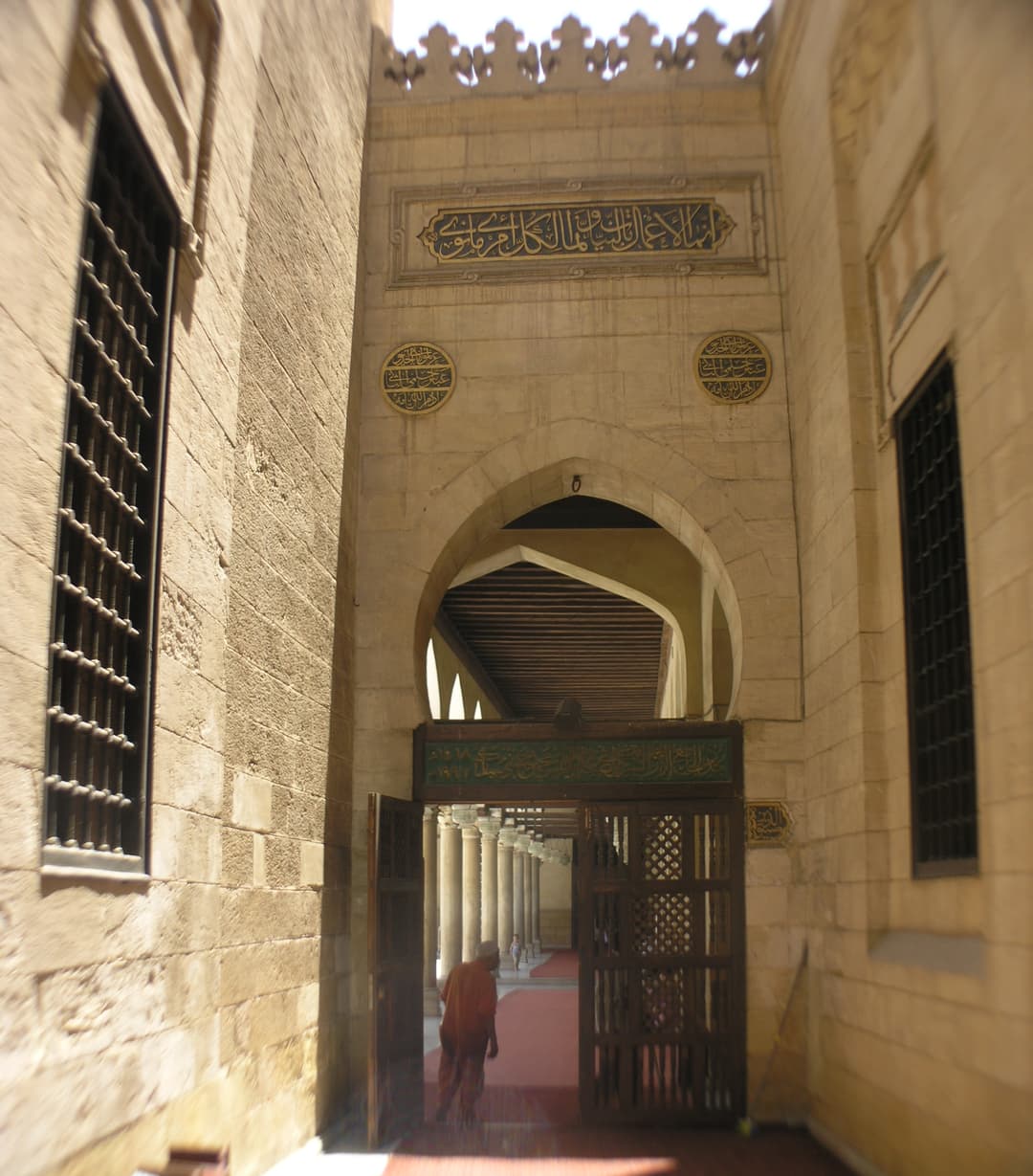 Arched stone portal with calligraphy leading into the prayer hall