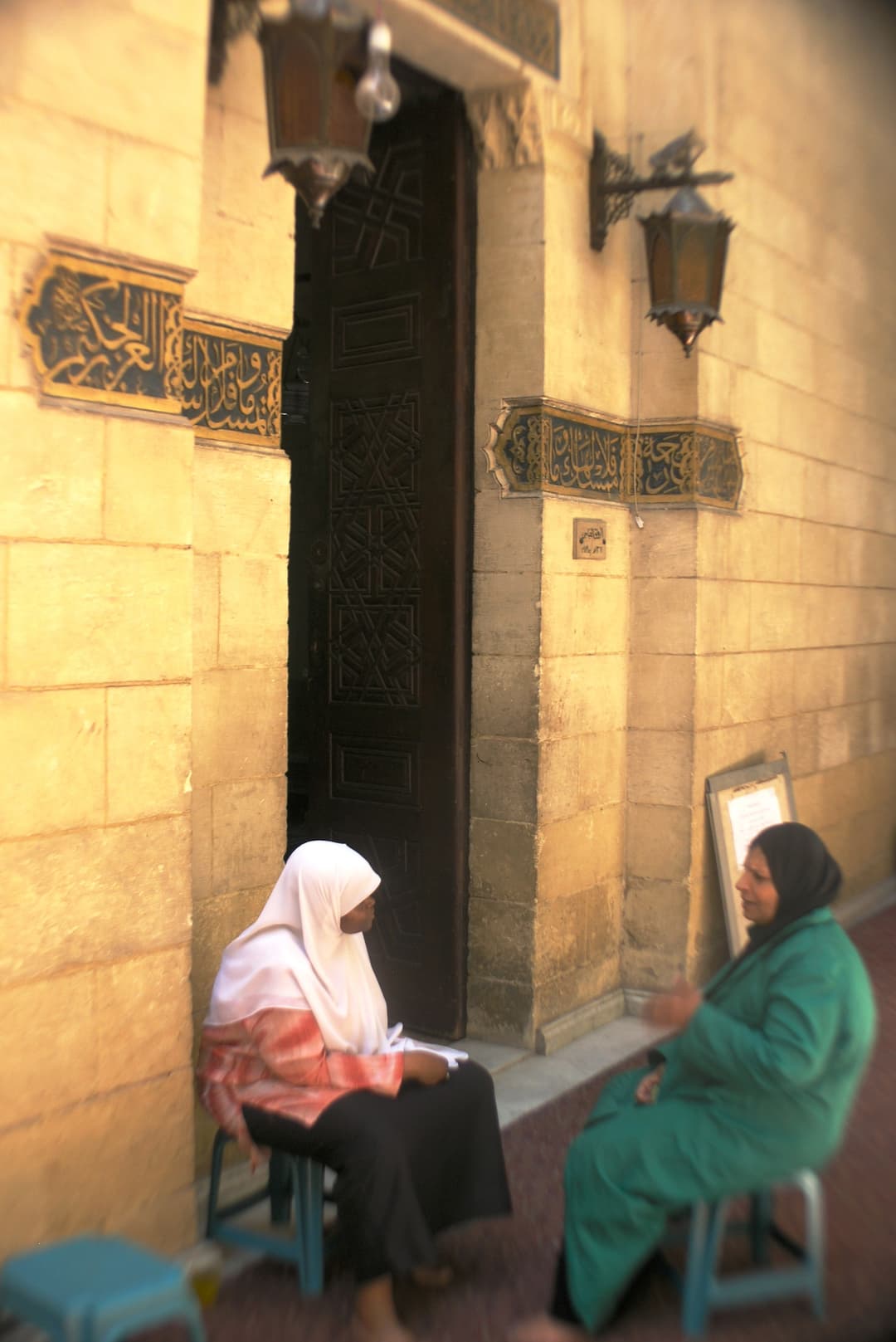Two women seated outside a carved doorway at Al-Azhar Mosque