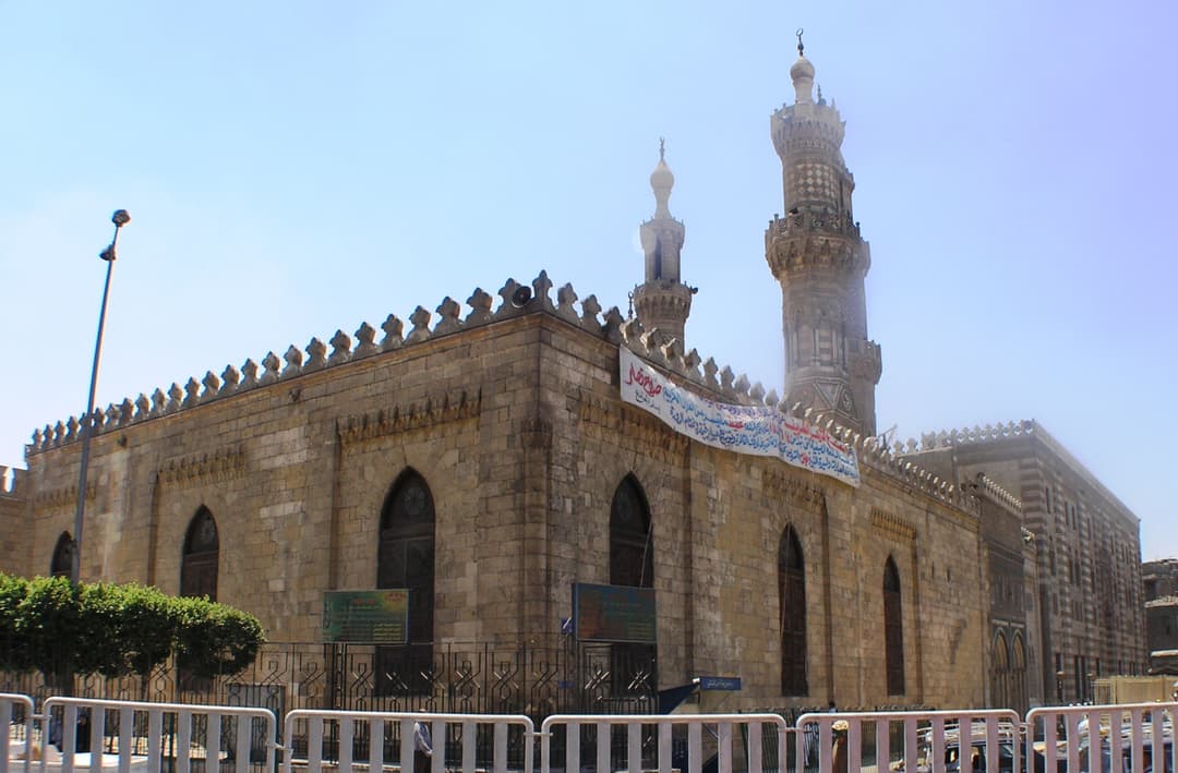 Exterior view of Al-Azhar Mosque's stone facade and towering minarets.