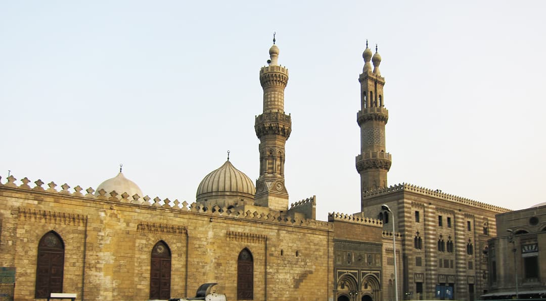 Exterior view of Al-Azhar Mosque featuring Mamluk minarets and domes.