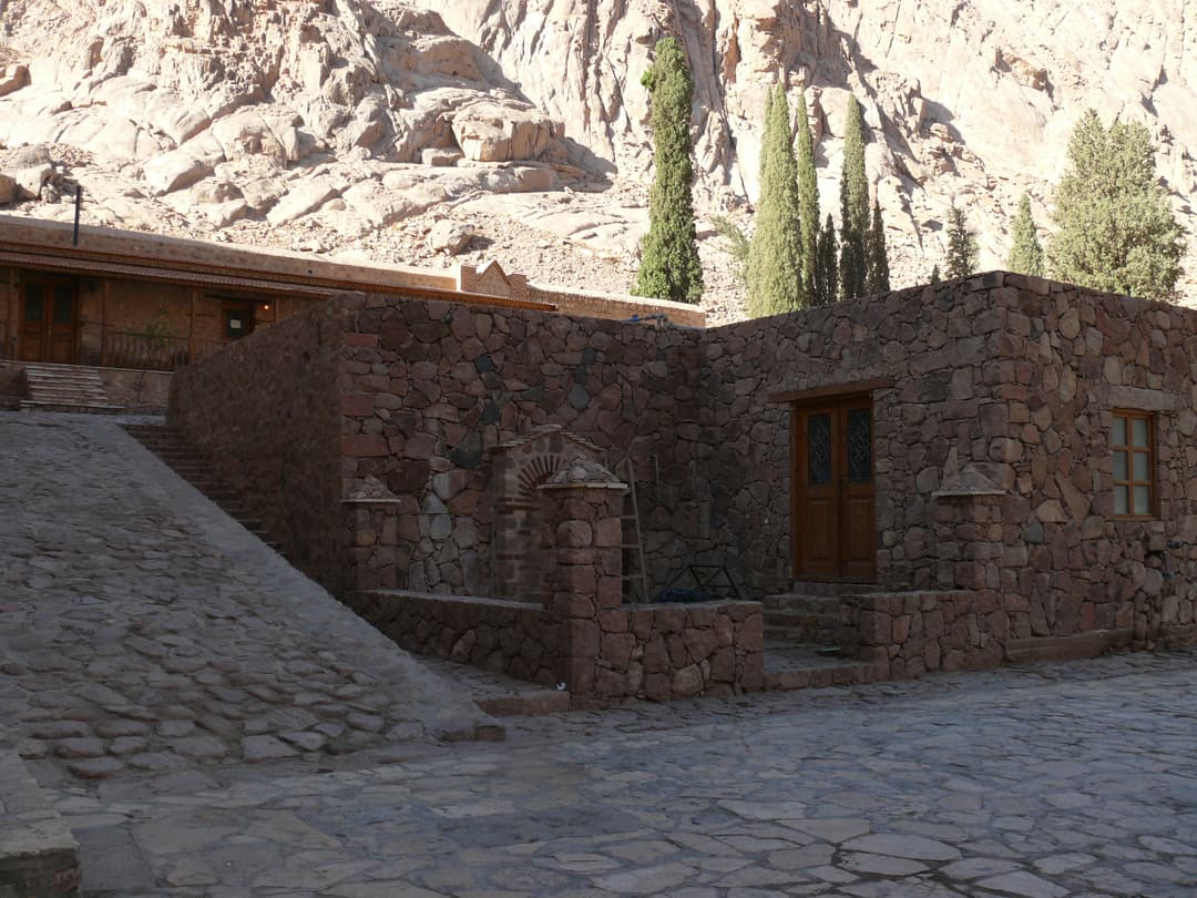 Stone buildings and paved courtyard beneath the cliffs of Wadi el-Deir