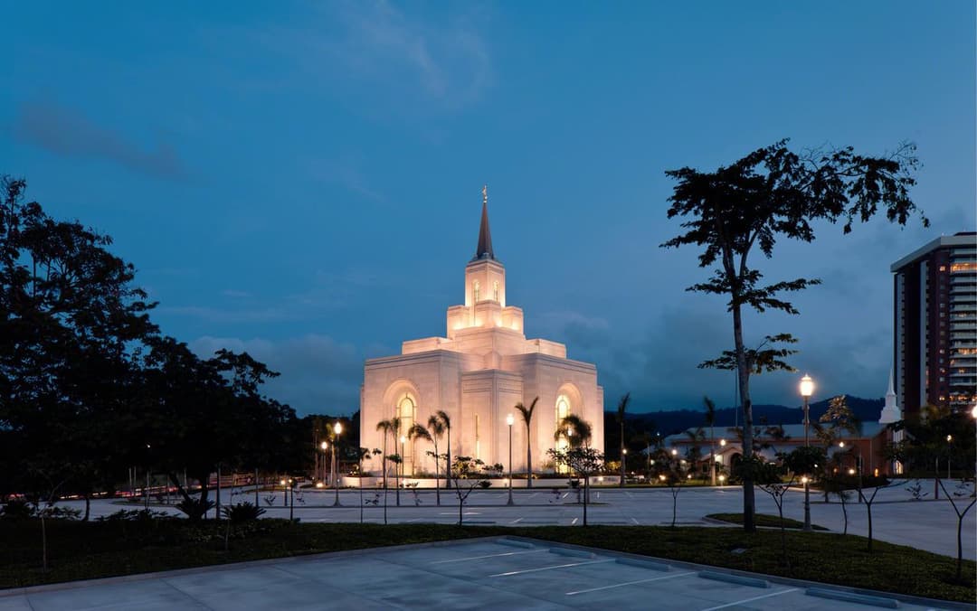 Exterior view of the illuminated San Salvador El Salvador Temple at twilight.