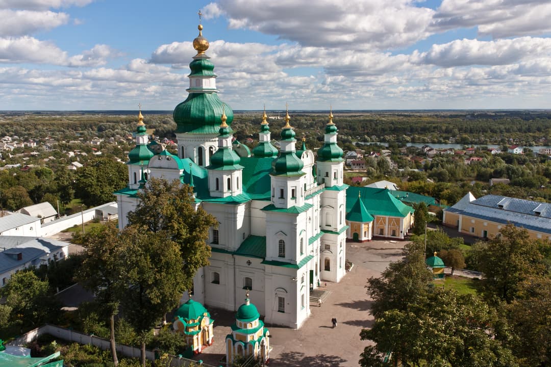 Aerial view of the cathedral with green domes, spires and surrounding grounds.