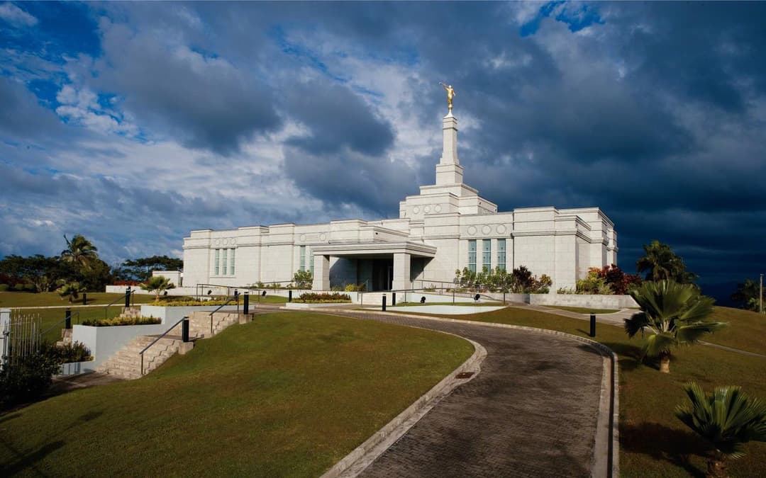 Exterior wide-angle view of the Suva Fiji Temple under a dramatic cloudy sky.