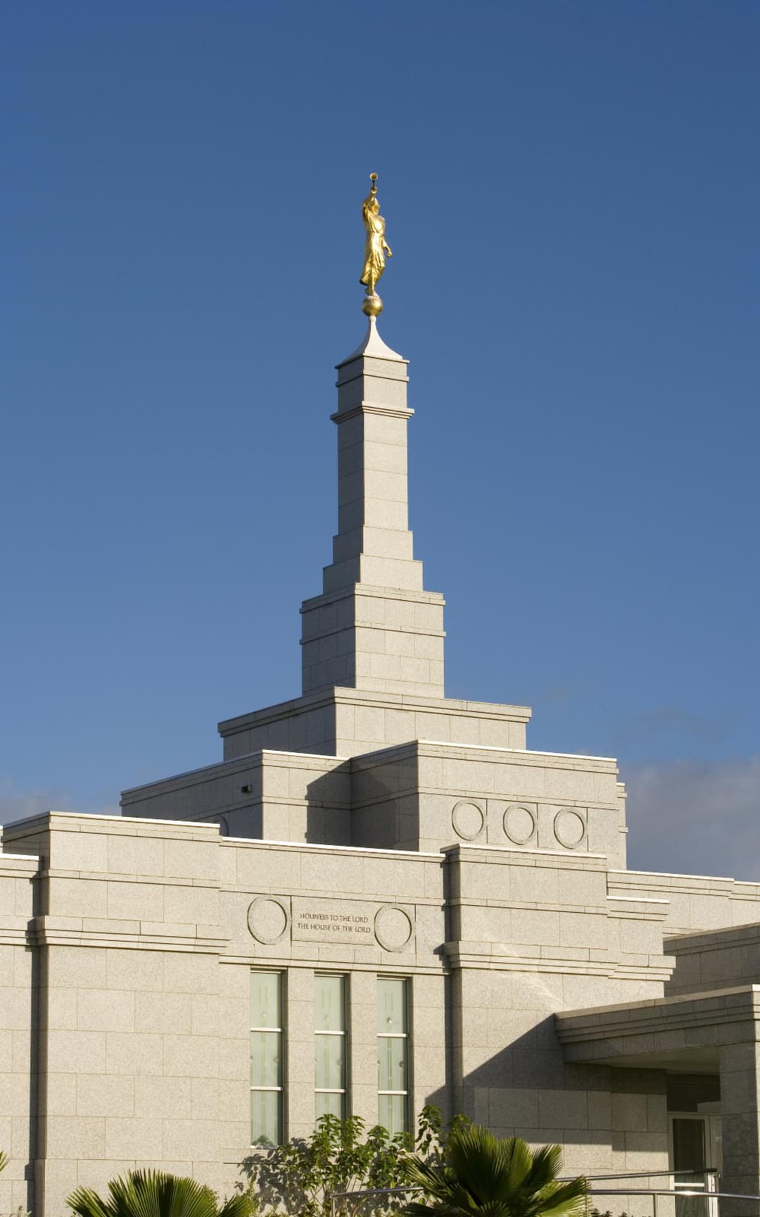 Suva Fiji Temple spire and upper facade under a clear blue sky.