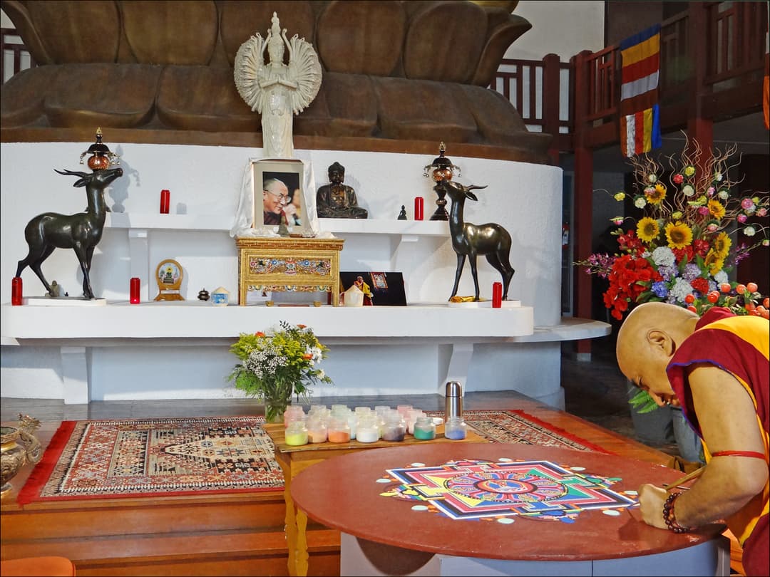Interior: Buddhist monk creating a sand mandala before the altar