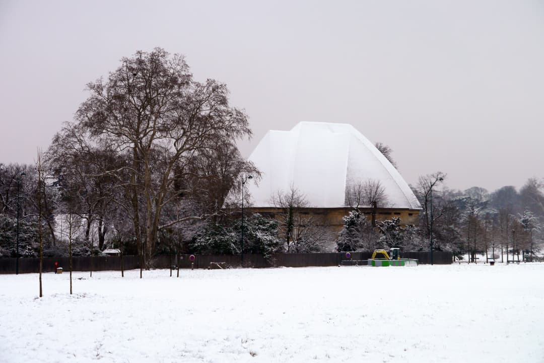 Distant view of the snow-covered Grande Pagode across a winter landscape.