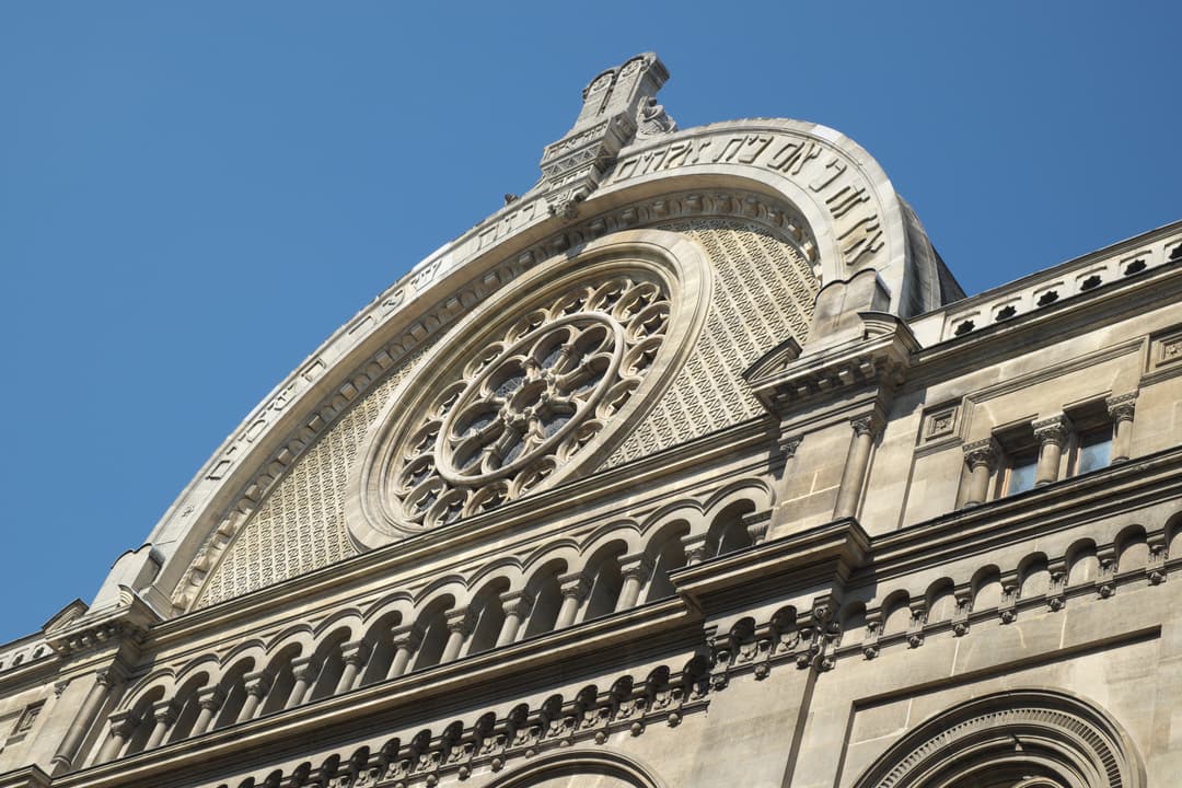 Low-angle view of the upper facade's arched pediment and rose window.