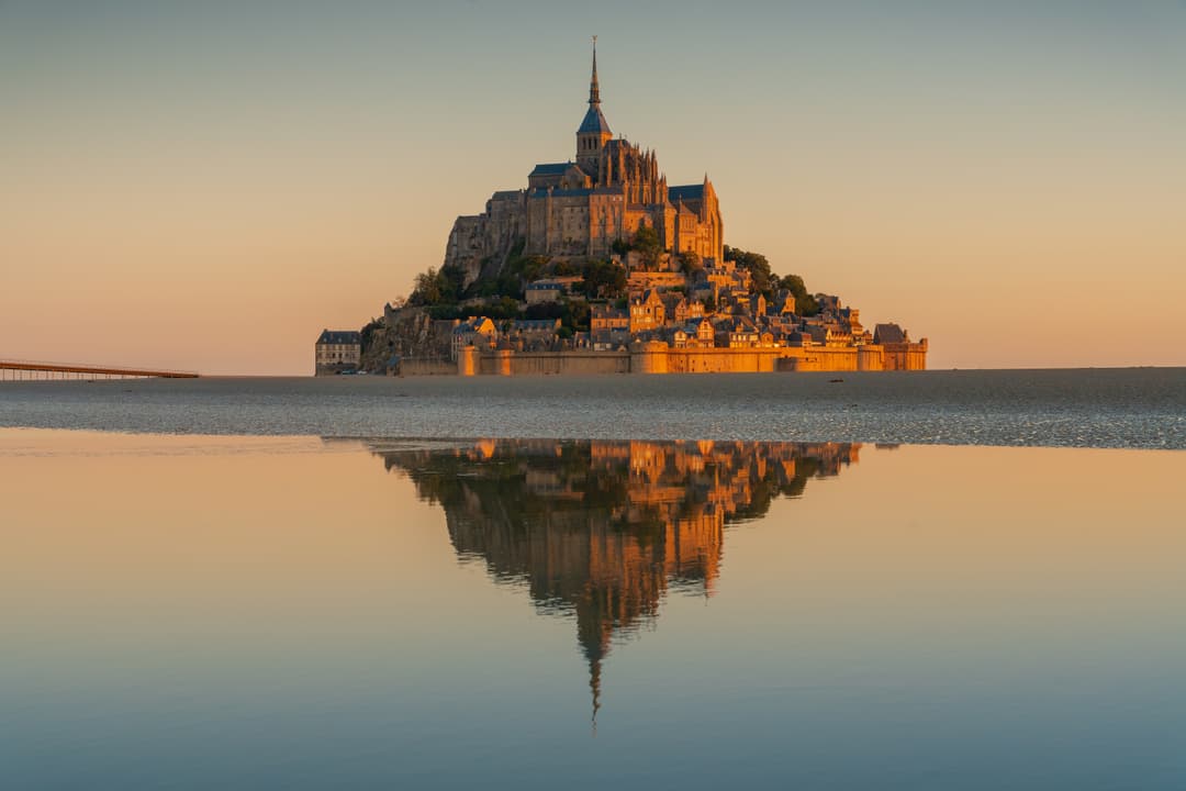 Mont-Saint-Michel reflected in tidal waters at golden hour