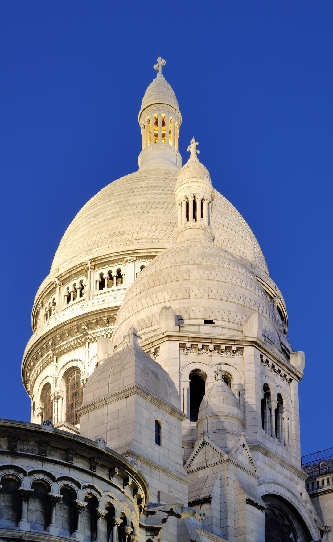 Low-angle view of the illuminated Sacré-Cœur domes at twilight.