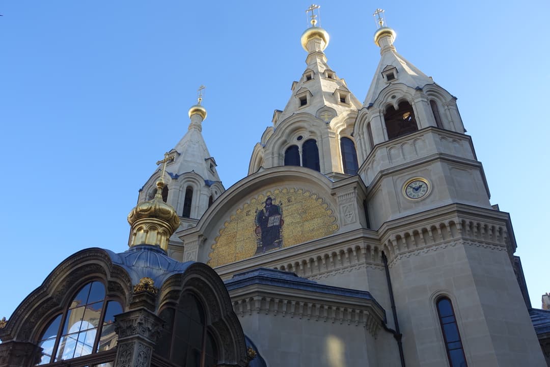 Low-angle exterior view of the golden domes, spires, and mosaic facade.