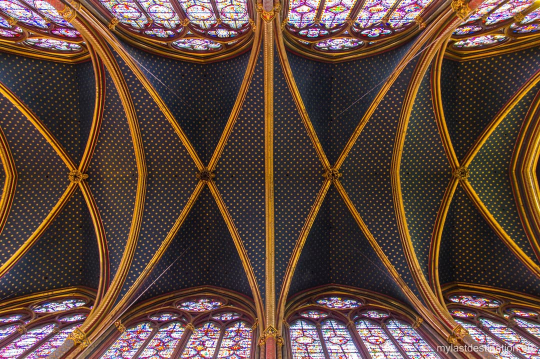 Starry blue vaulted ceiling and stained glass inside Sainte-Chapelle.