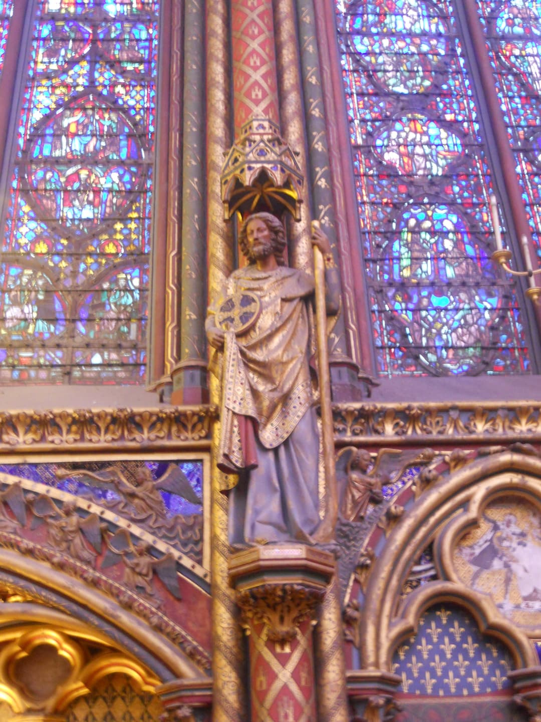 Statue of an apostle framed by stained glass inside the Sainte-Chapelle.