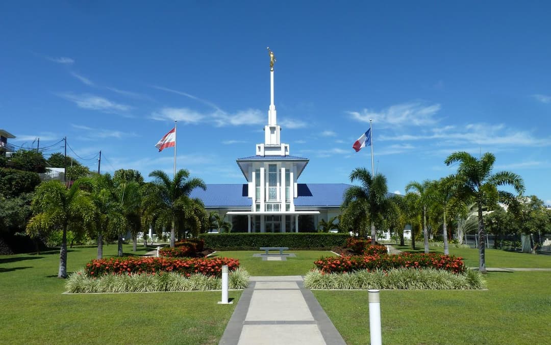 Papeete Tahiti Temple, daytime front exterior with gardens and flags.