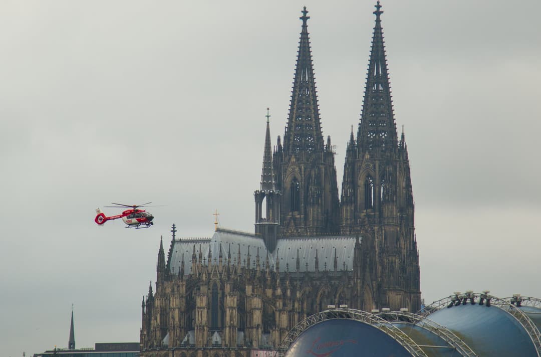 A rescue helicopter flying past the twin spires of Cologne Cathedral.