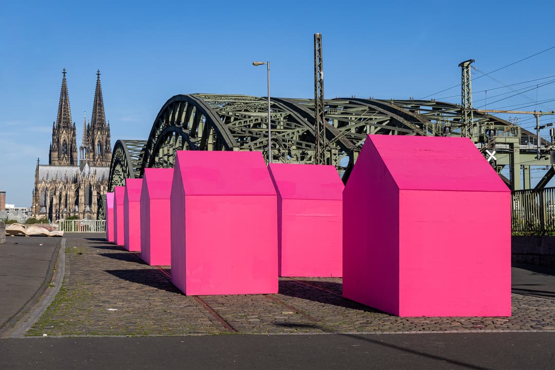 Cologne Cathedral and Hohenzollern Bridge behind pink house sculptures