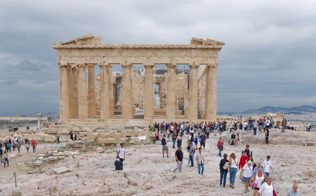 Western facade of the Parthenon with visitors on the Acropolis grounds.