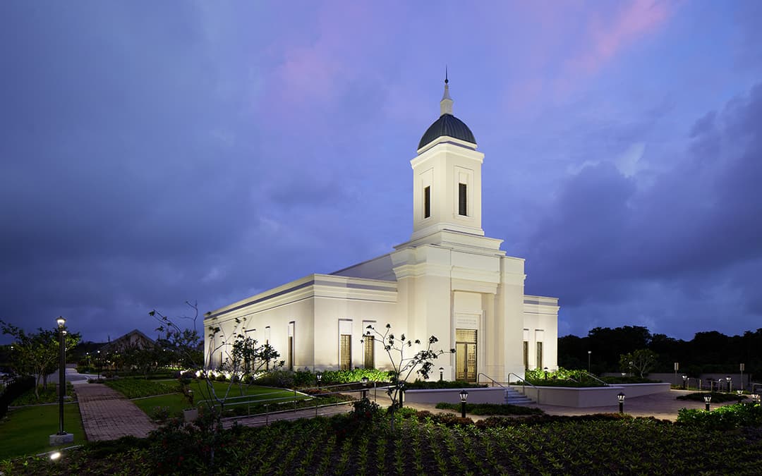 Exterior view of the illuminated Yigo Guam Temple at twilight.