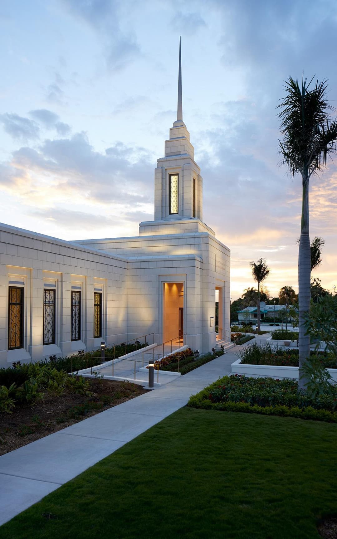 Exterior view of the temple entrance and illuminated spire at twilight.