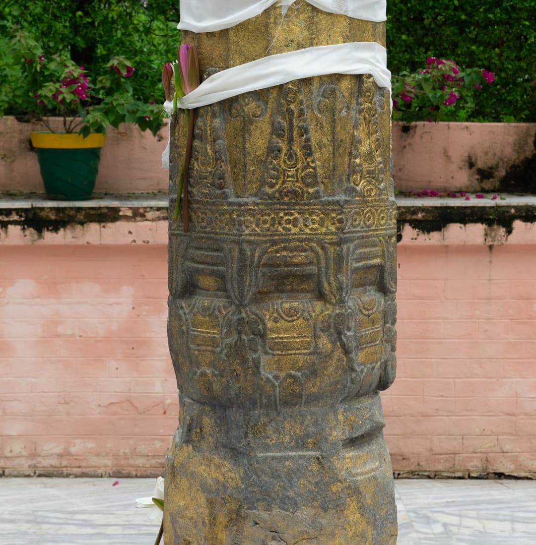 Ornate stone pillar with cloth and lotus flower at Mahabodhi Temple.