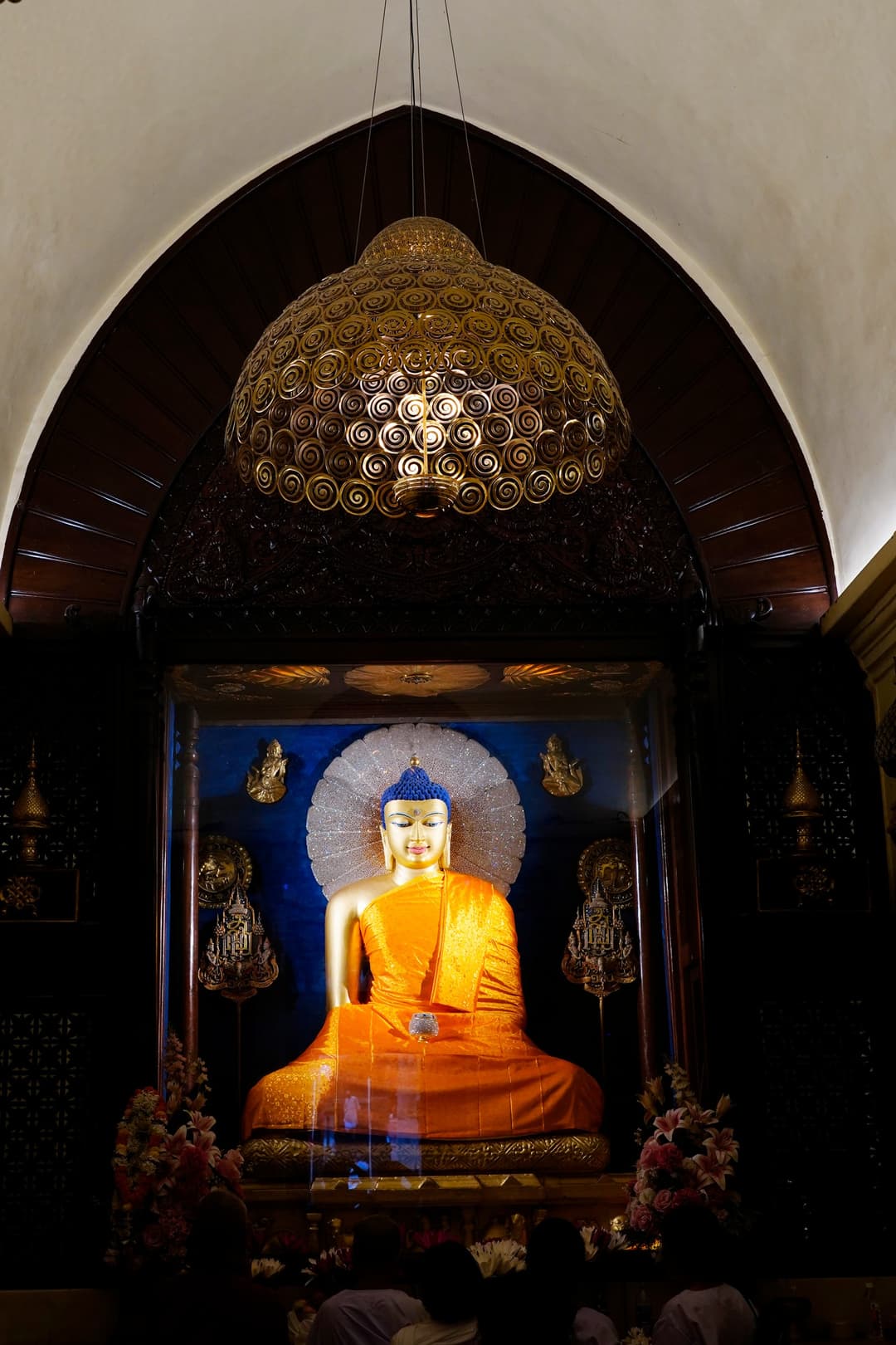 Mahabodhi Temple interior: Buddha statue and ornate chandelier.