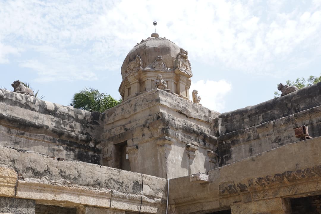 Low-angle view of a domed stone corner shrine with Nandi sculptures