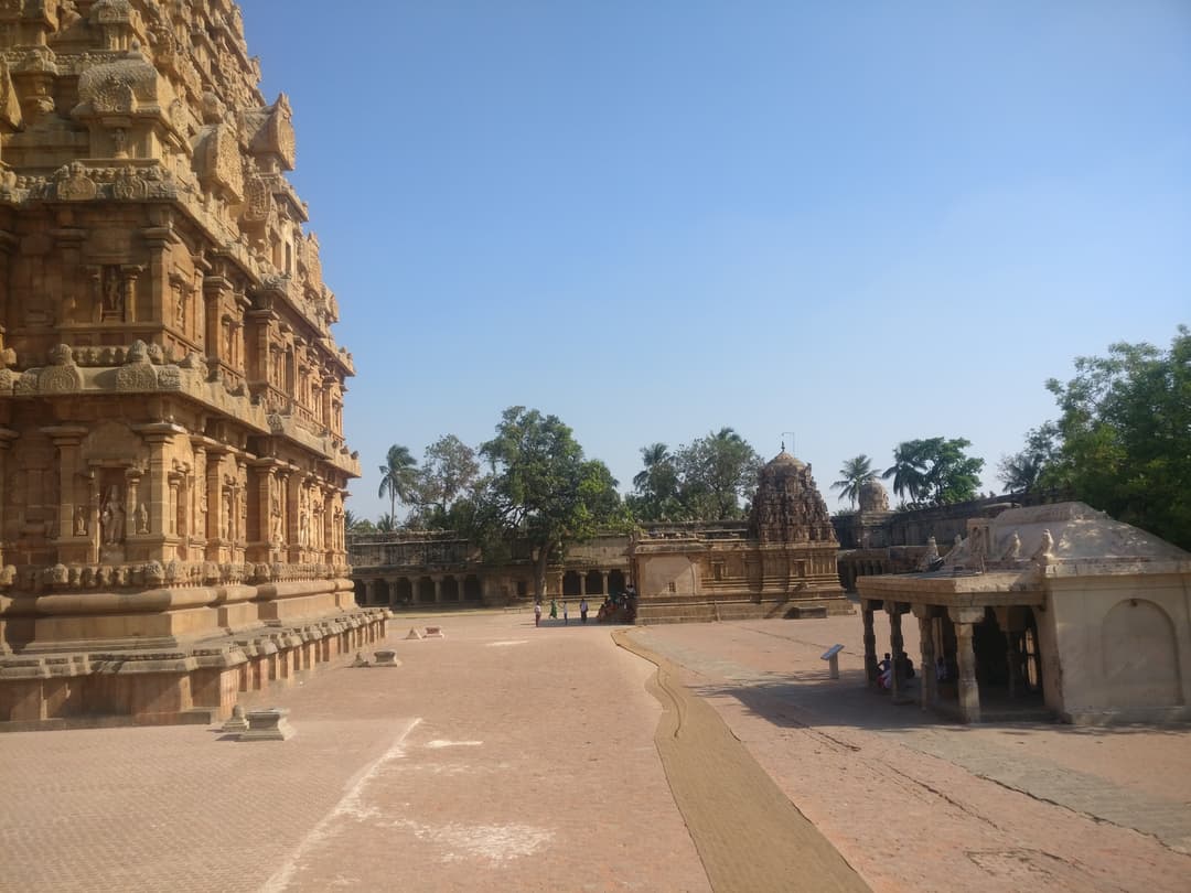 Sunlit courtyard showing the carved vimana base and subsidiary shrines.