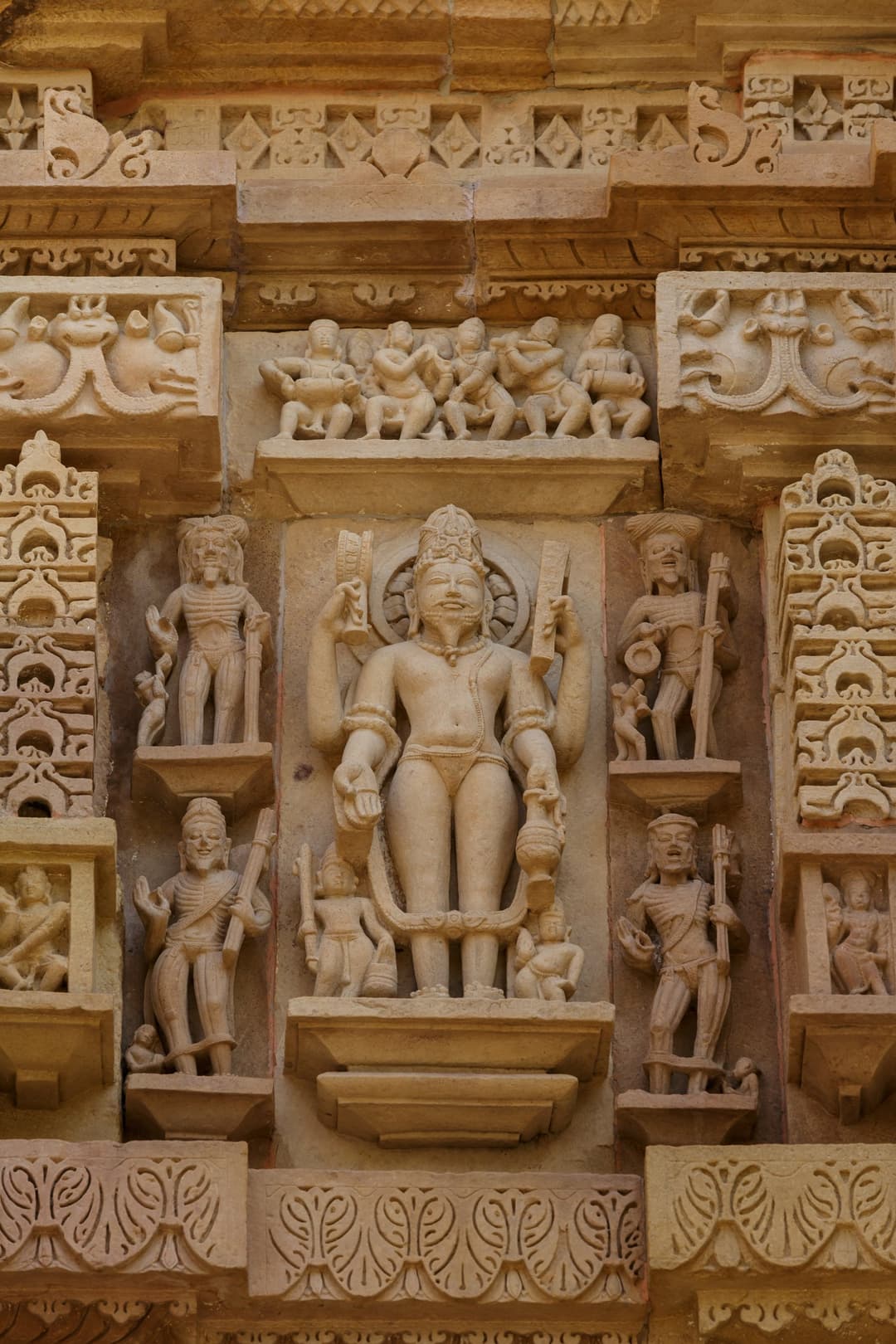 Carved relief of a standing deity flanked by ascetics on the temple facade.