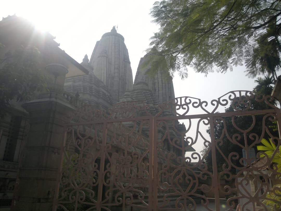 Backlit view of the sandstone spires framed by an ornate iron gate.