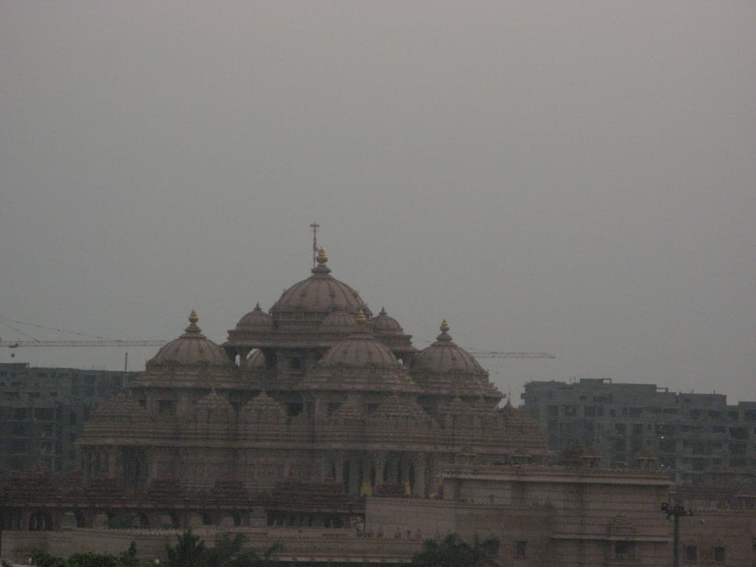 Exterior view of Akshardham Temple's carved domes on a hazy, overcast day.
