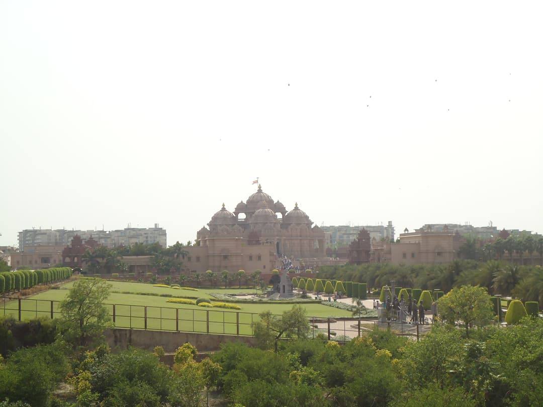 Distant view of Akshardham Mandir and manicured gardens in daylight.