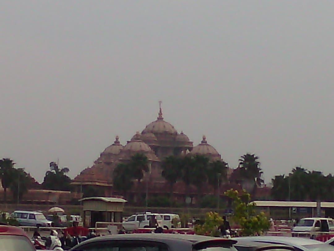Distant view of Akshardham Temple's carved domes and spires on a hazy day.