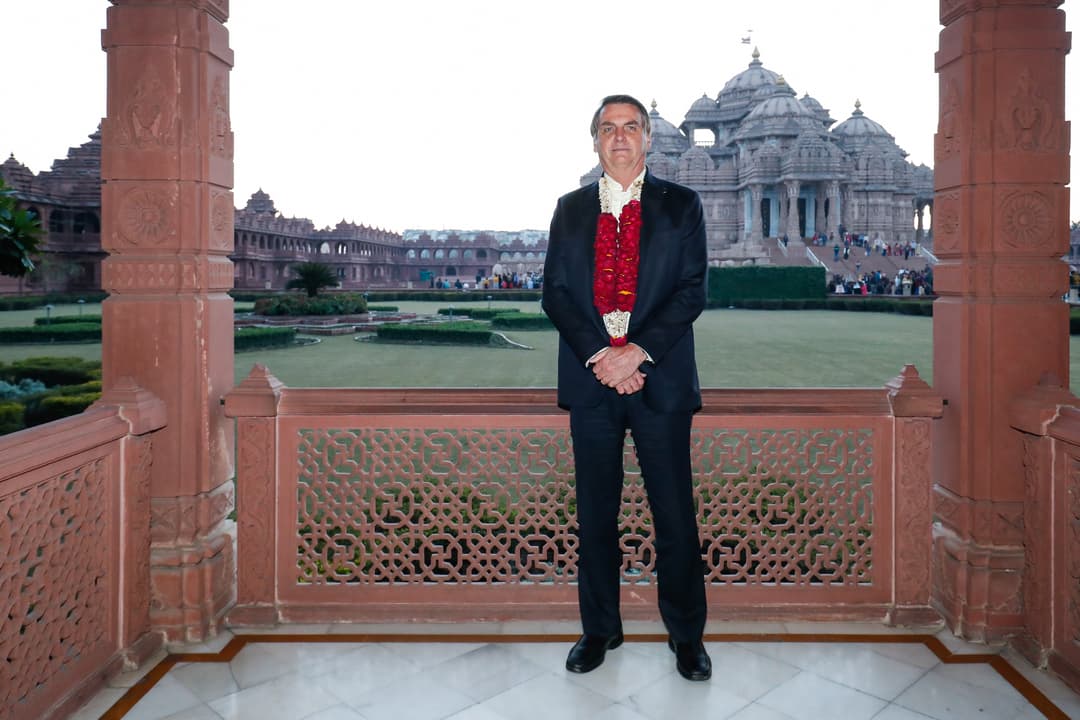 Carved sandstone pavilion framing a view of the Akshardham temple and grounds.