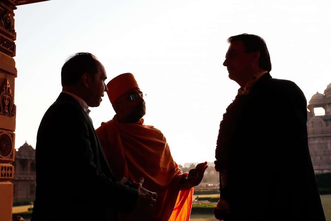 Silhouetted visitors conversing with a monk at Akshardham.