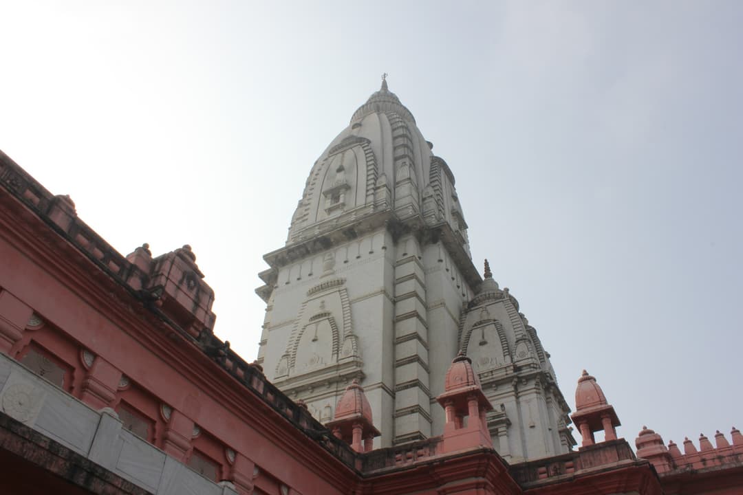 Low-angle view of the towering shikhara above red sandstone pavilions.