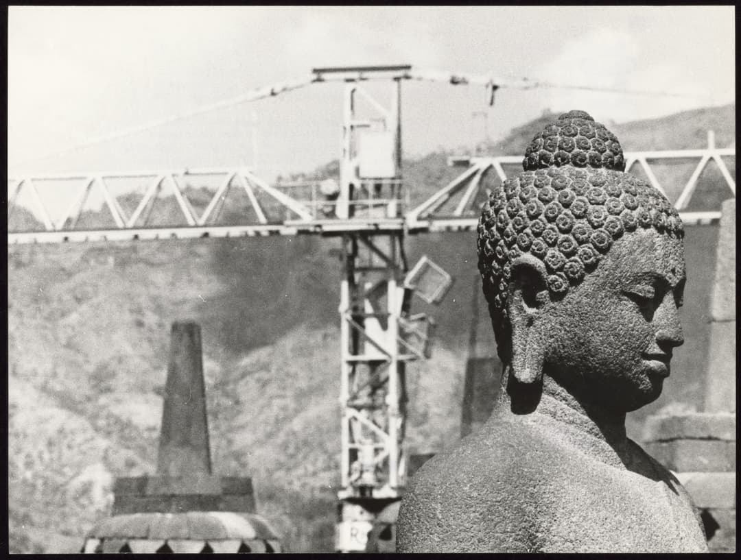 Buddha statue profile, stupa and construction crane in background.