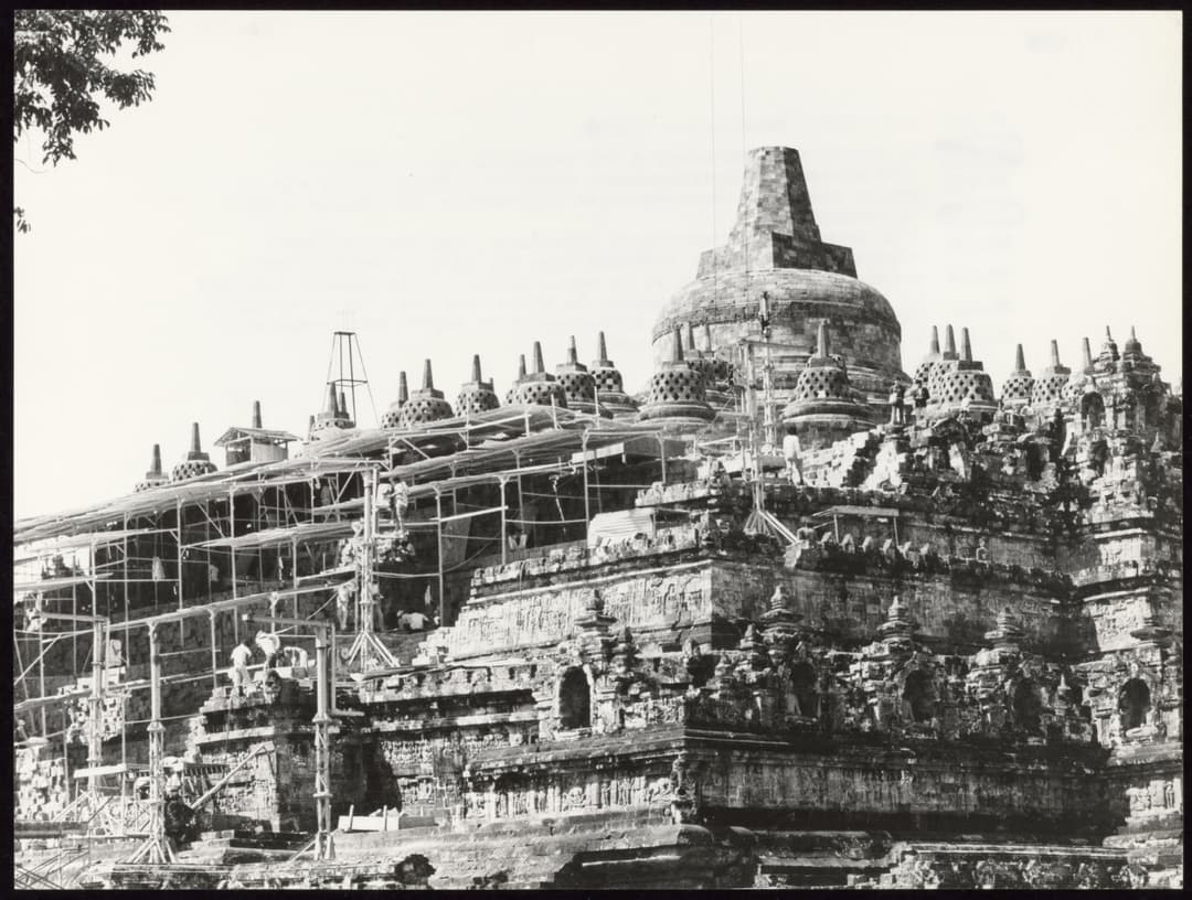 Borobudur Temple with scaffolding, workers visible.