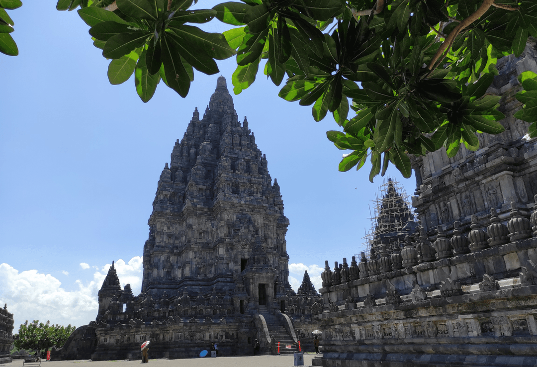 The towering Shiva temple at Prambanan framed by overhead foliage.