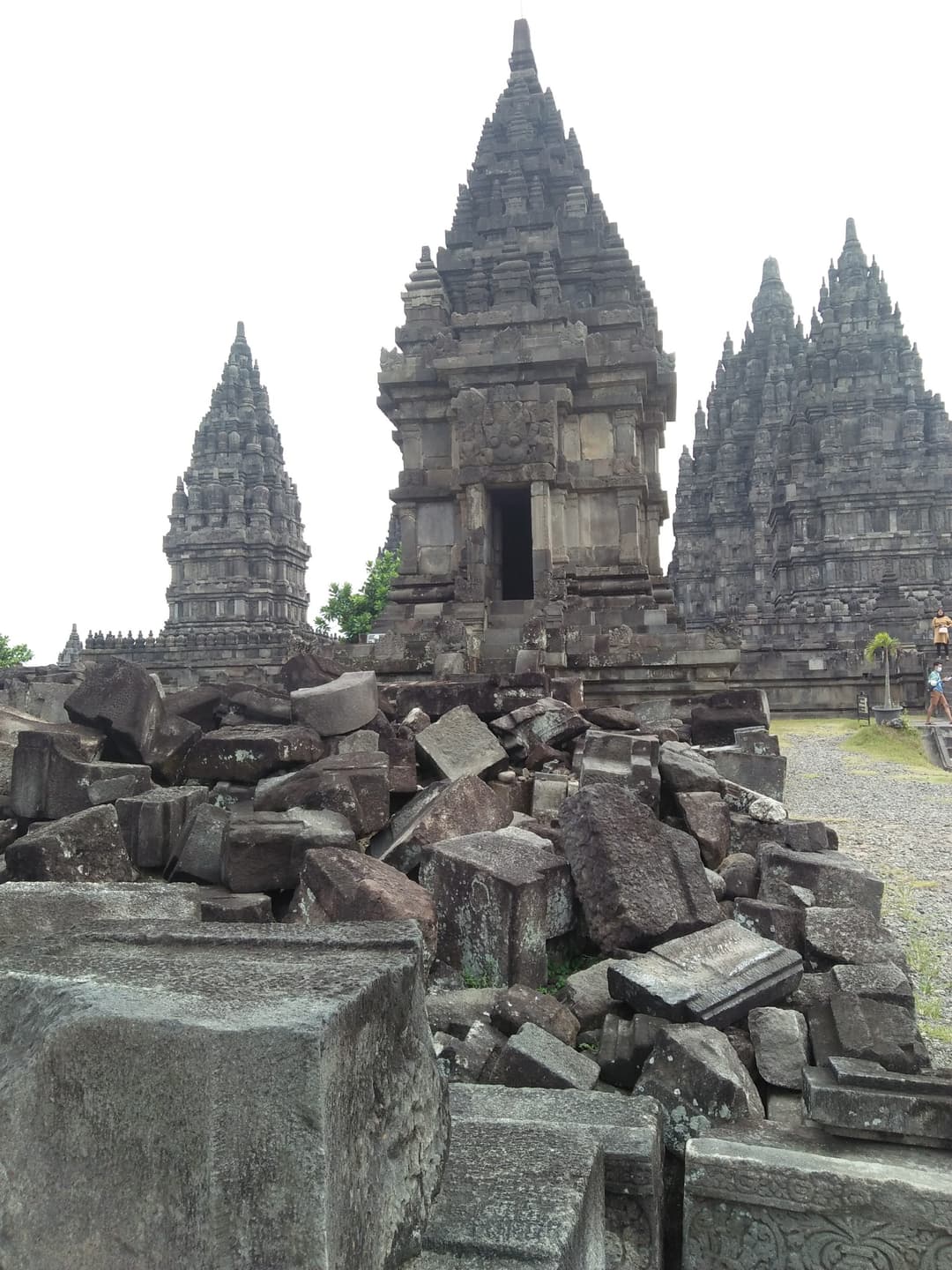 Carved stone ruins before towering spires at Prambanan temple.