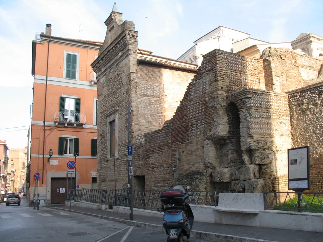 Ancient Roman brick ruins viewed from the street in daytime.