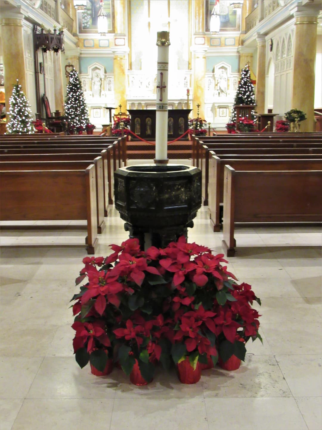 Church interior with baptismal font, paschal candle, and poinsettias